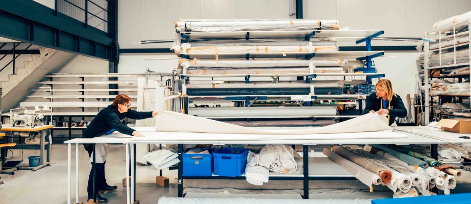 Atelier met stoffenrollen en werktafels waar het woningtextiel op maat wordt gemaakt