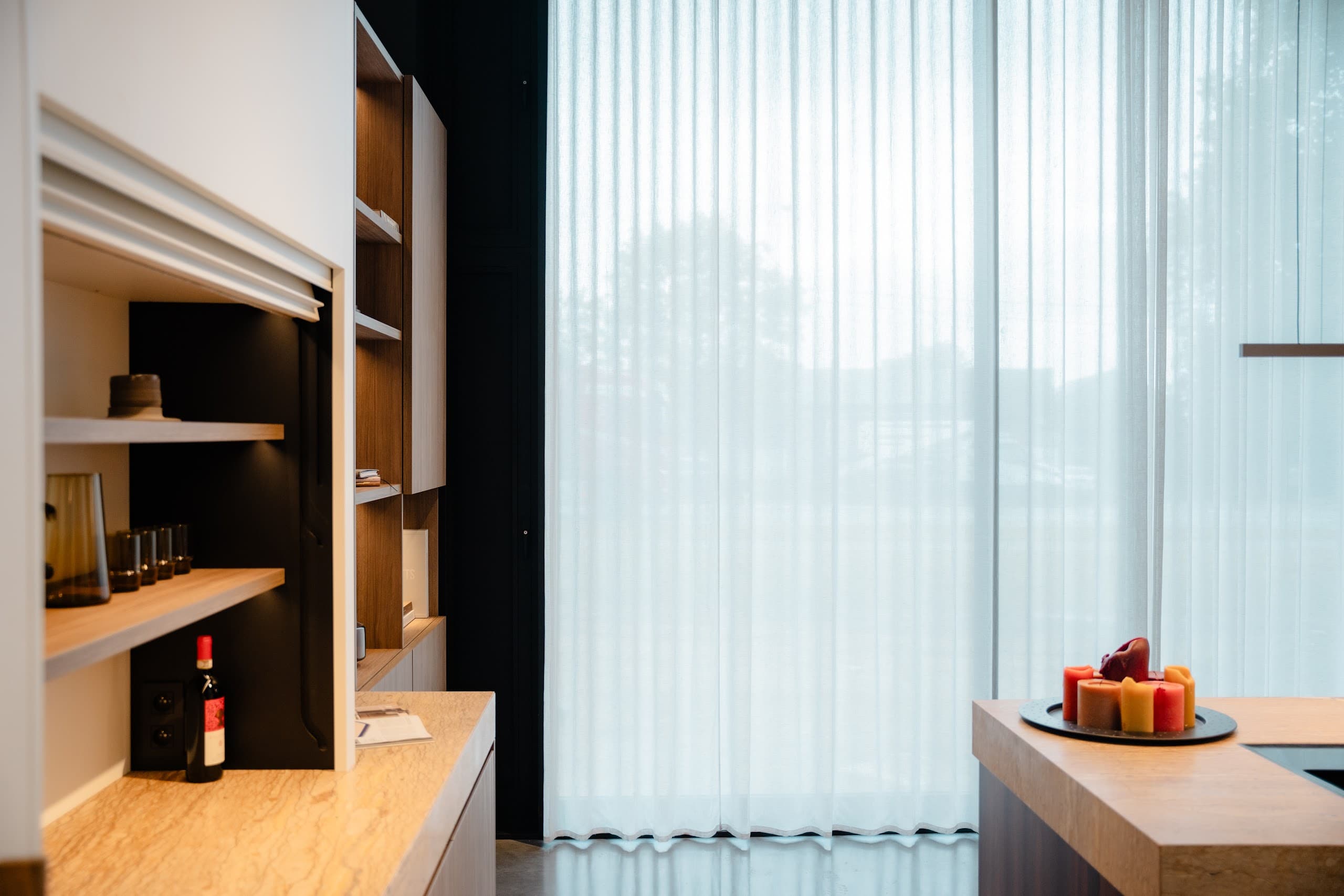 Zithoek bij de bar in de showroom met transparante gordijnen langs de gevel