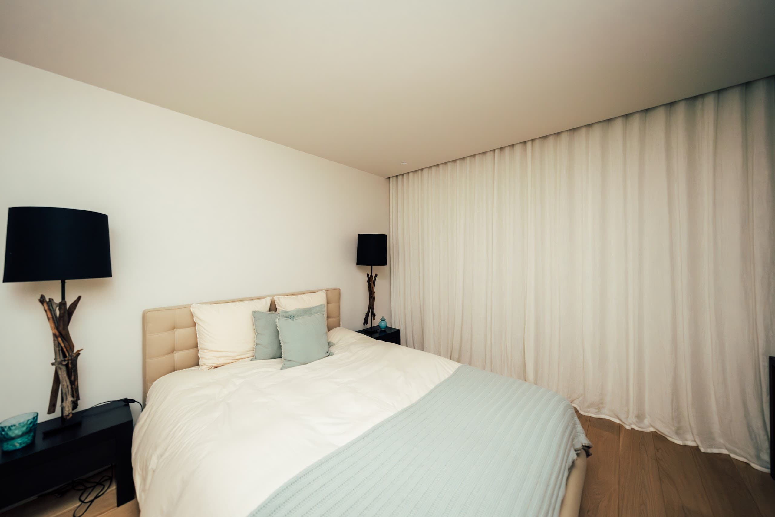 Rustige slaapkamer met luchtige gordijnen langs de wand